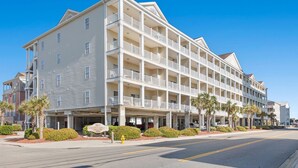 A multi-story hotel with balconies, a parking area, and palm trees. - Spacious 5 bedroom oceanview condo - Cherry Grove Beach (North Myrtle Beach)