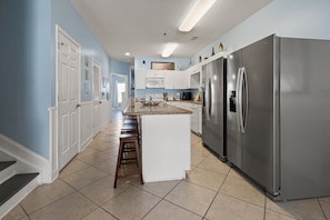 A kitchen with a central island, stainless steel appliances, and a light blue wall. - Spacious 5 bedroom oceanview condo - Cherry Grove Beach (North Myrtle Beach)