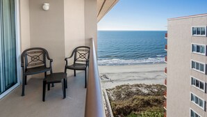 Un balcon avec deux chaises et une vue sur la plage et l’océan.