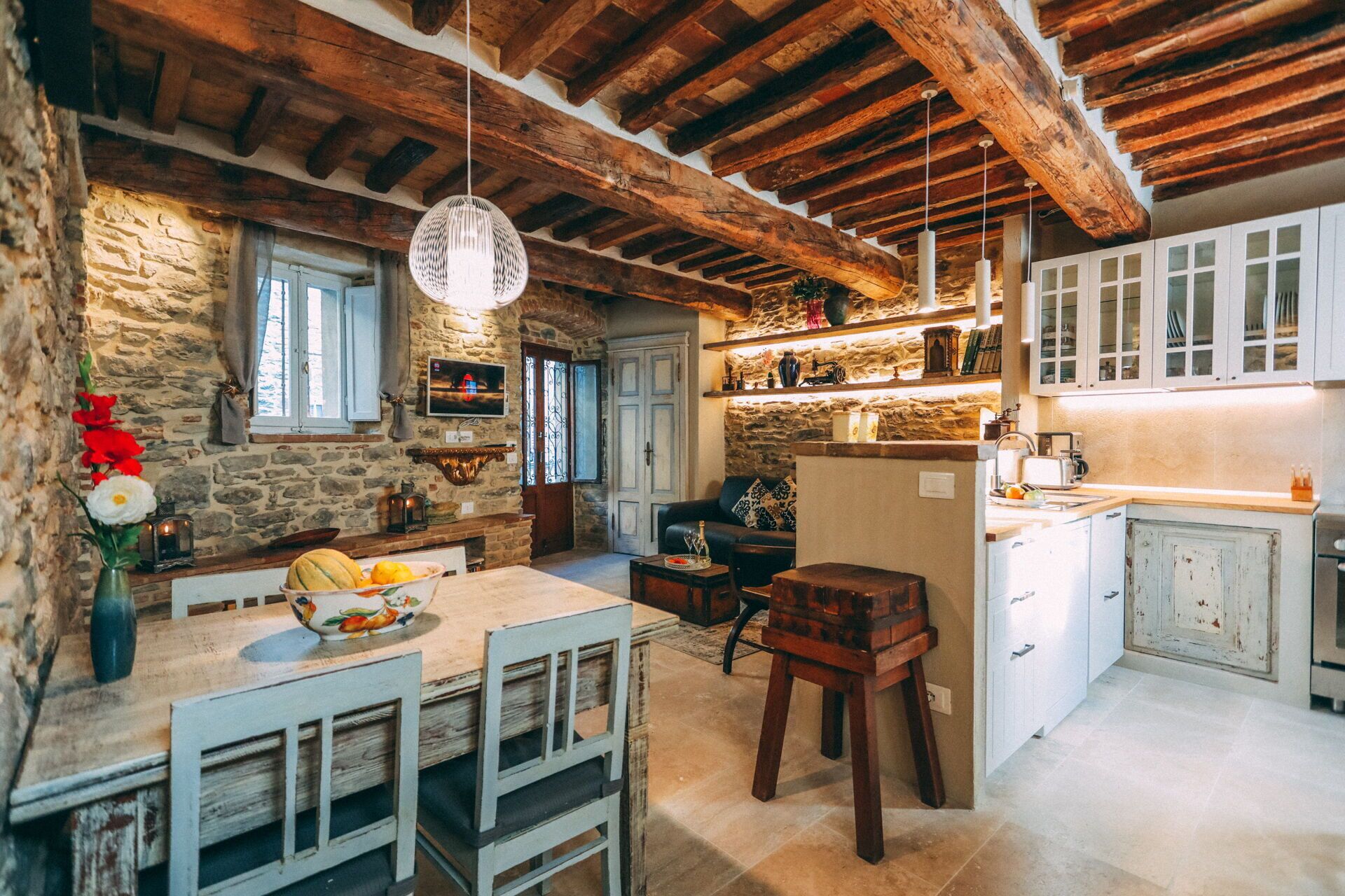 Una cucina rustica con pareti in pietra, travi in legno e un'area pranzo con tavolo e sedie.