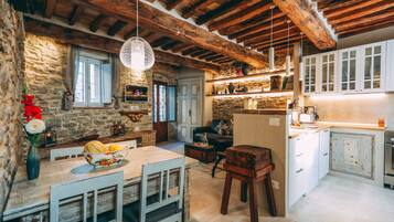 Una cucina rustica con pareti in pietra, travi in legno e un'area pranzo con tavolo e sedie.