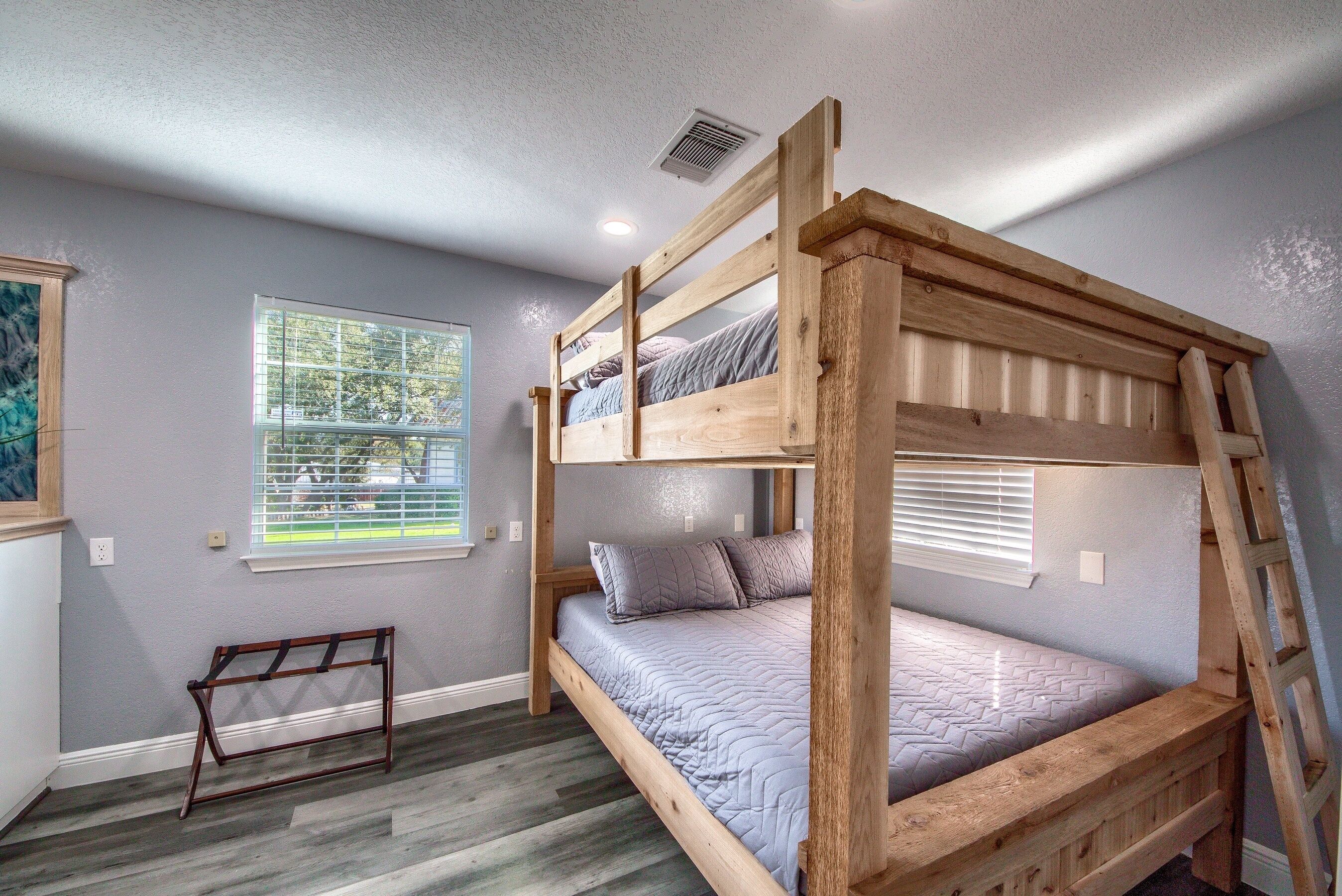 A bunk bed with a wooden frame and a window with blinds.