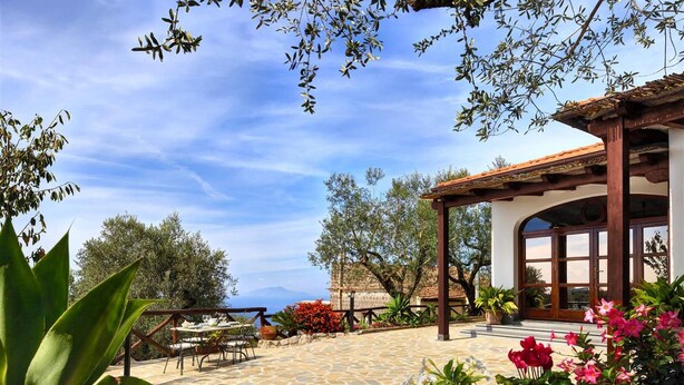 An outdoor patio with a stone floor, a wooden pergola, and a table set for dining. - Tulipano - A Charming and Peaceful Hillside Villa With Lovely Views (Massa Lubrense)