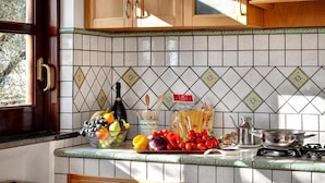 A kitchen with wooden cabinets, a tiled backsplash, and various kitchen items on the counter. - Tulipano - A Charming and Peaceful Hillside Villa With Lovely Views (Massa Lubrense)