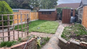 A backyard with a wooden fence, a shed, and a garden area with a lawn mower.