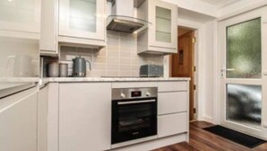 A modern kitchen with white cabinetry, a built-in oven, and a stainless steel range hood.