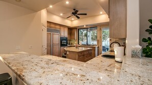 A modern kitchen with granite countertops, wooden cabinets, a built-in oven, and a ceiling fan. - Casa Buenaluxurious Retreat w/2 Masters & Views! (Phoenix)