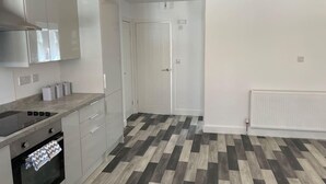 A modern kitchen with white cabinets, a built-in oven, and a herringbone-patterned floor. - Impeccable 1-bed Apartment in Chesterfield (Chesterfield)