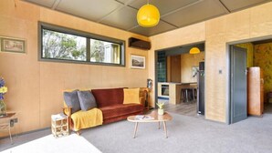 Un salón moderno con un sofá rojo, un cojín amarillo y una mesa de centro. Hay un ventanal y vistas al exterior.