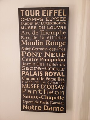 Un letrero negro con texto blanco que enumera monumentos parisinos famosos.