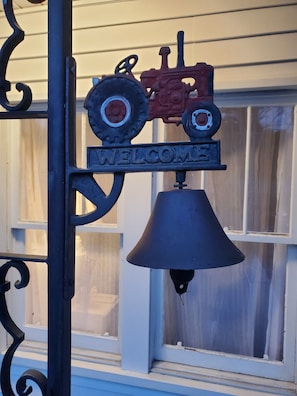 Un letrero de metal con un tractor y la palabra 'WELCOME' sobre una campana.