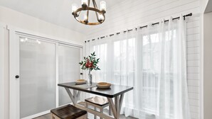 A dining area with a table and bench, a chandelier, and a window with sheer curtains. - Renovated Ranch Home. Pet Friendly, Game Room, Fire Pit, Grill, Covered Porch (Woodstock)