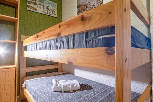 A bunk bed with a wooden frame and a grey mattress.
