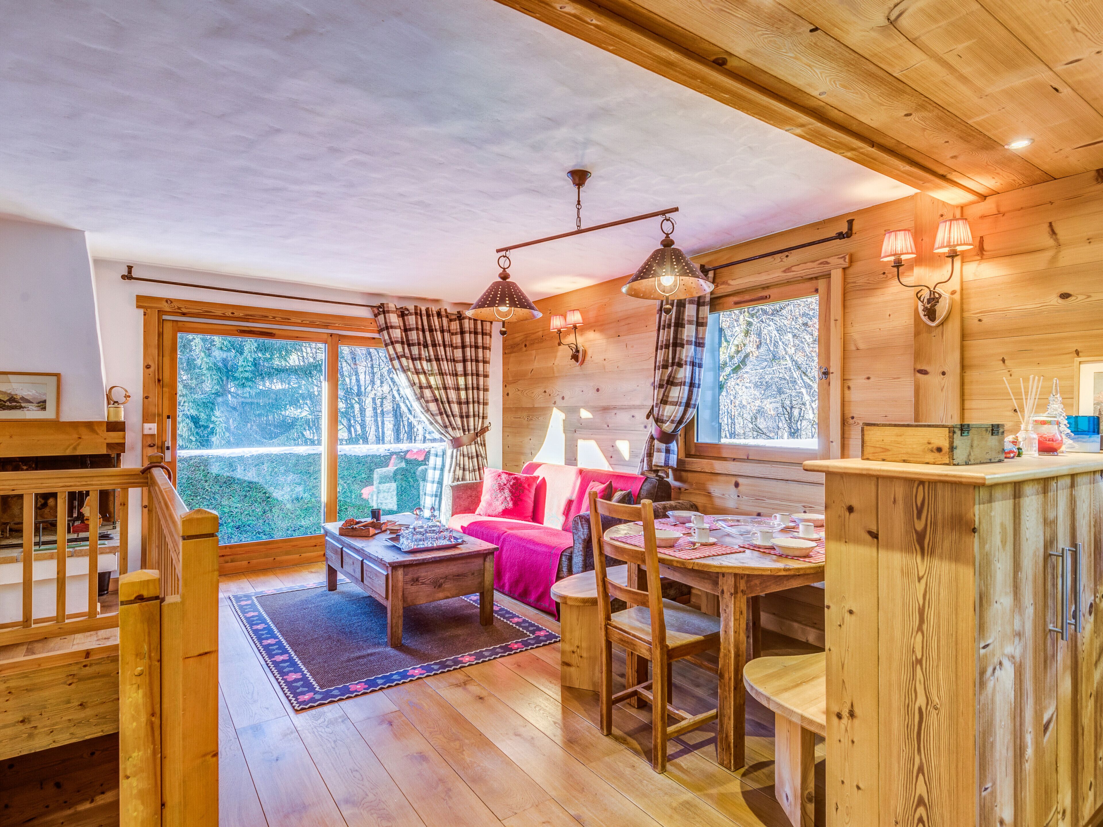 A cozy cabin interior with a wooden dining table, chairs, and a sofa.