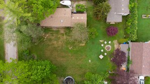 Ein Luftbild eines Wohngebiets mit einem Haus, einer Garage und einem Garten mit Gartenmöbeln.