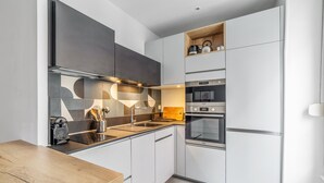 A modern kitchen with a wooden countertop, stainless steel appliances, and a built-in oven. - Appartement Anatha - Welkeys (Lyon)