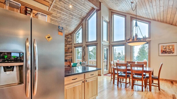 A modern kitchen with a stainless steel refrigerator, wooden cabinets, and a large island with a black countertop. - 22STR-00367 Fairplay Cabin ~ 6 Mi to Downtown! (Fairplay)
