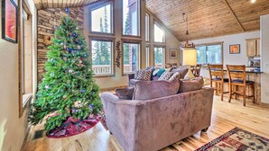 A cozy living room with a large window, a wooden ceiling, and a Christmas tree. - 22STR-00367 Fairplay Cabin ~ 6 Mi to Downtown! (Fairplay)