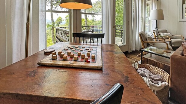 Een ruime kamer met een grote houten tafel, een schaakbord en een eethoek met stoelen.