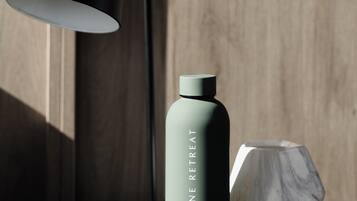 A modern lamp, a water bottle, and a hexagonal object on a wooden surface.