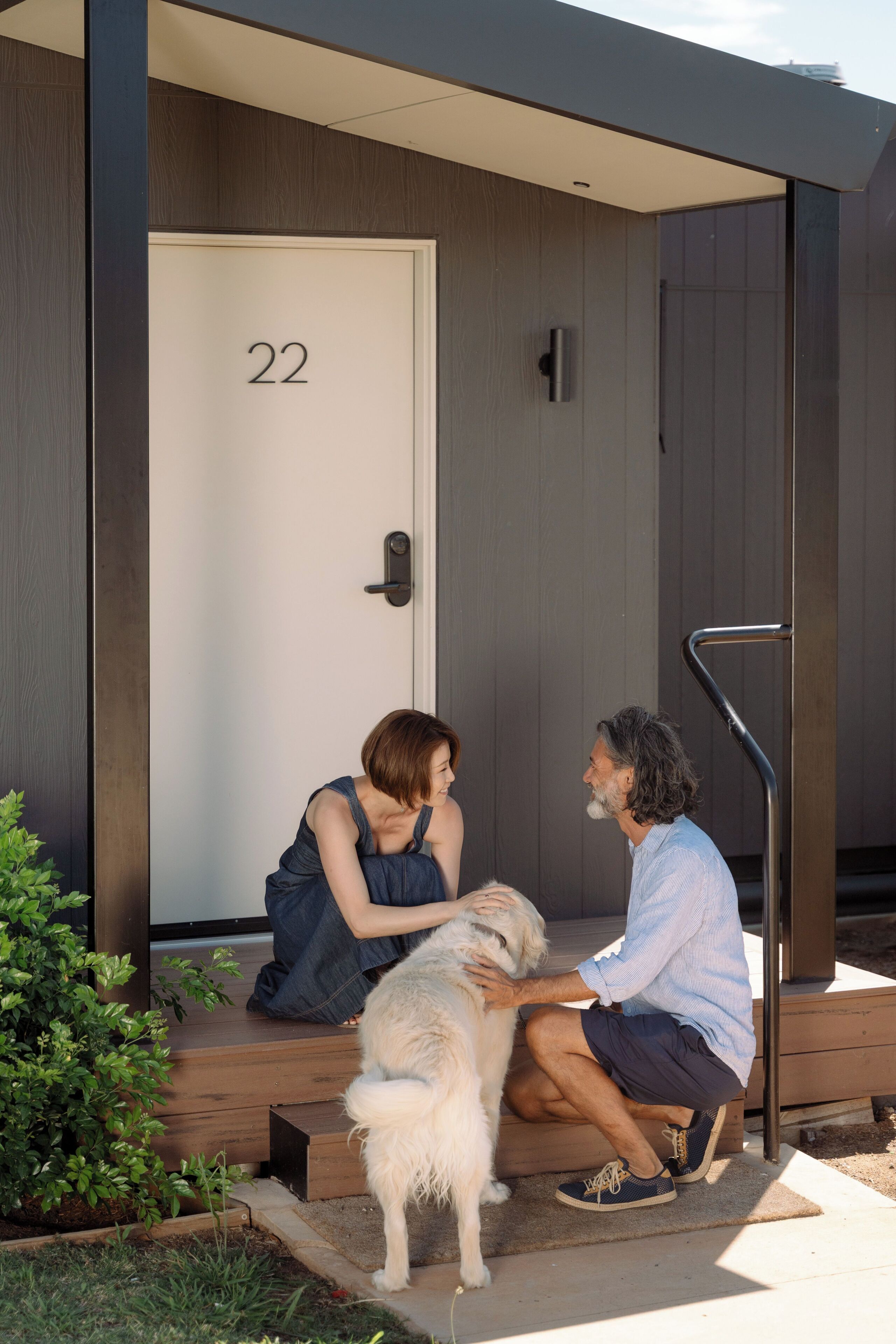 Un bâtiment moderne avec une porte portant le numéro « 22 » et un petit espace extérieur doté d’un escalier et d’une rambarde en métal.