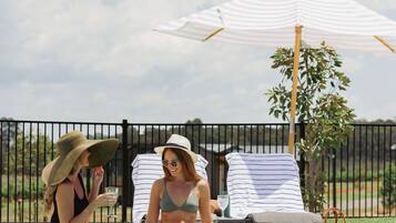 Una piscina al aire libre, sillones reclinables de piscina