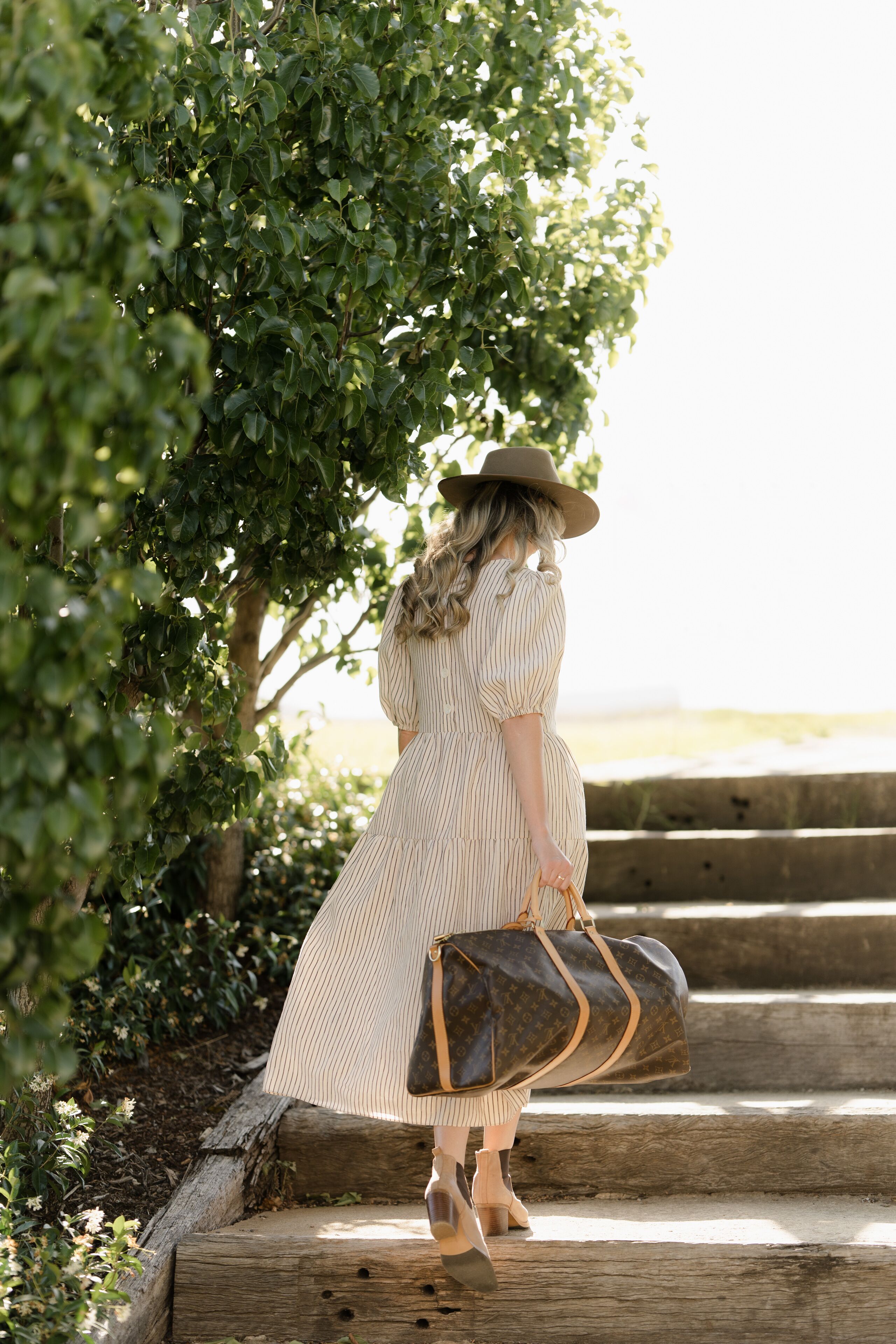 A person descending a wooden staircase in a garden setting.