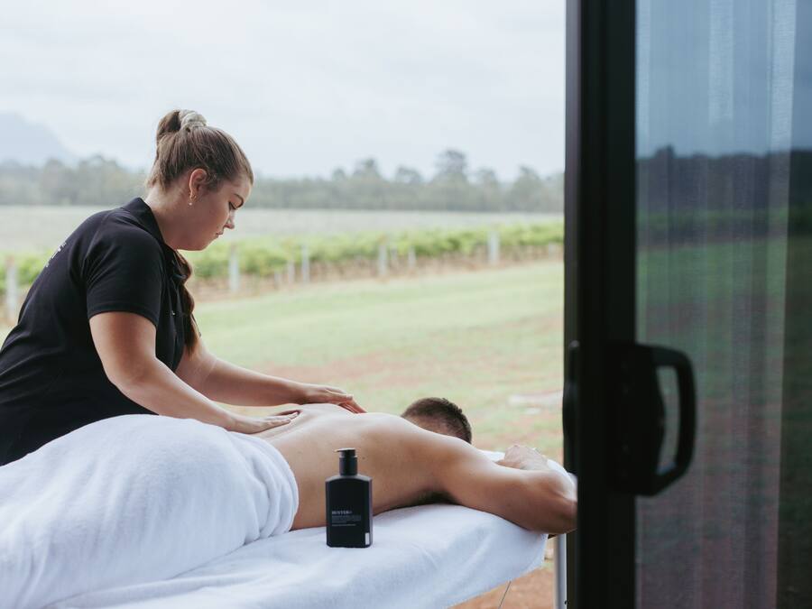 A massage therapy session in a room with a large window overlooking a vineyard.