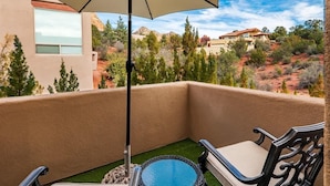 Un balcon avec une chaise, une petite table ronde et un parasol.