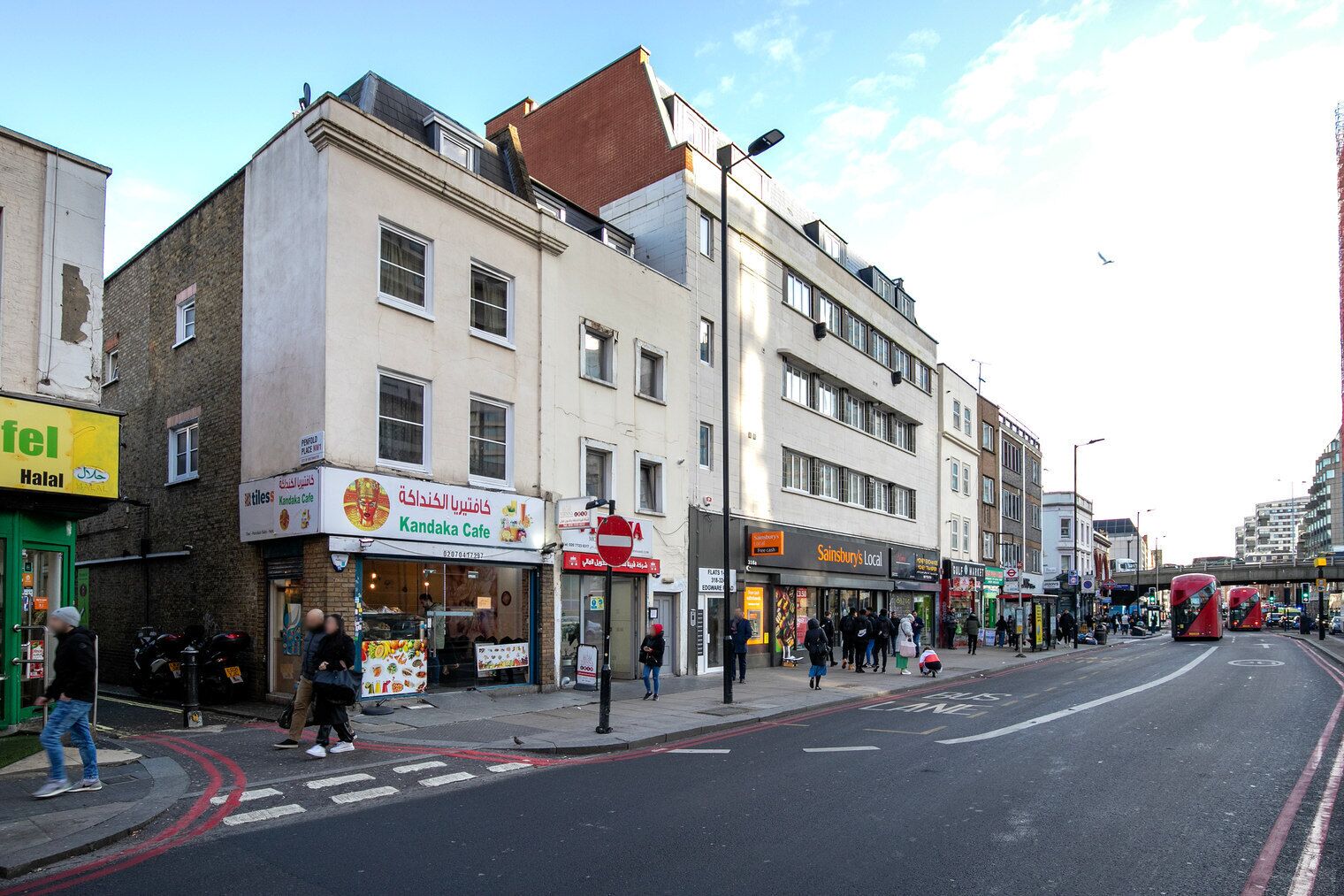 A street with shops including a cafe and a local store.