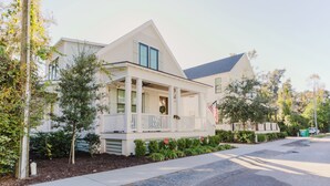 A white house with a porch, a flag, and a garden. - Old Town Bluffton Beaches and Birdies House (Bluffton)