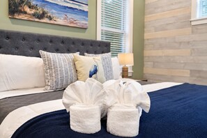 A hotel room with a bed, pillows, a blue blanket, and two white towels.