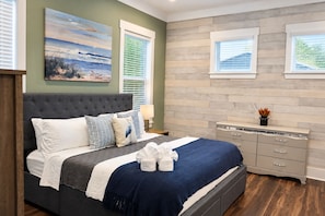 A bedroom with a bed, bedside tables, a dresser, and artwork on the walls.