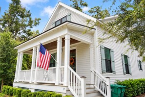 A white house with a porch, a flag, and a number 7 on the front.