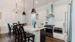 A modern kitchen with a central island, stainless steel appliances, and pendant lighting. - Old Town Bluffton Beaches and Birdies House (Bluffton)