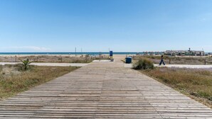 A wooden boardwalk leading to a beach with a clear sky.