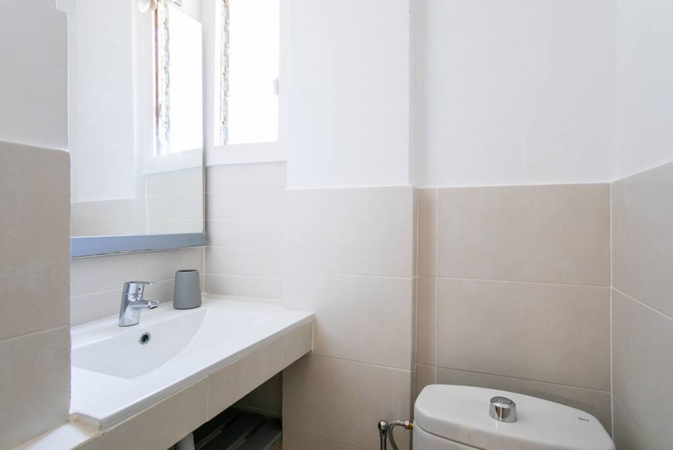 A bathroom with a white sink, mirror, and toilet.