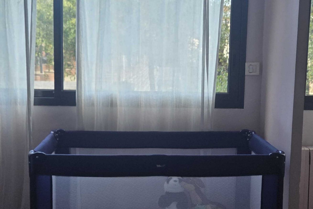 Una habitación con ventana, cama y cortina.