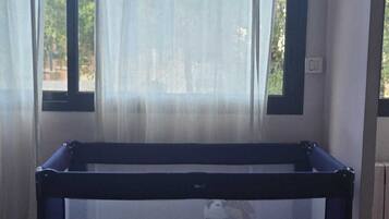 Una habitación con ventana, cama y cortina.