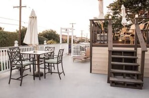 A patio with outdoor seating, a wooden staircase, and a white railing.