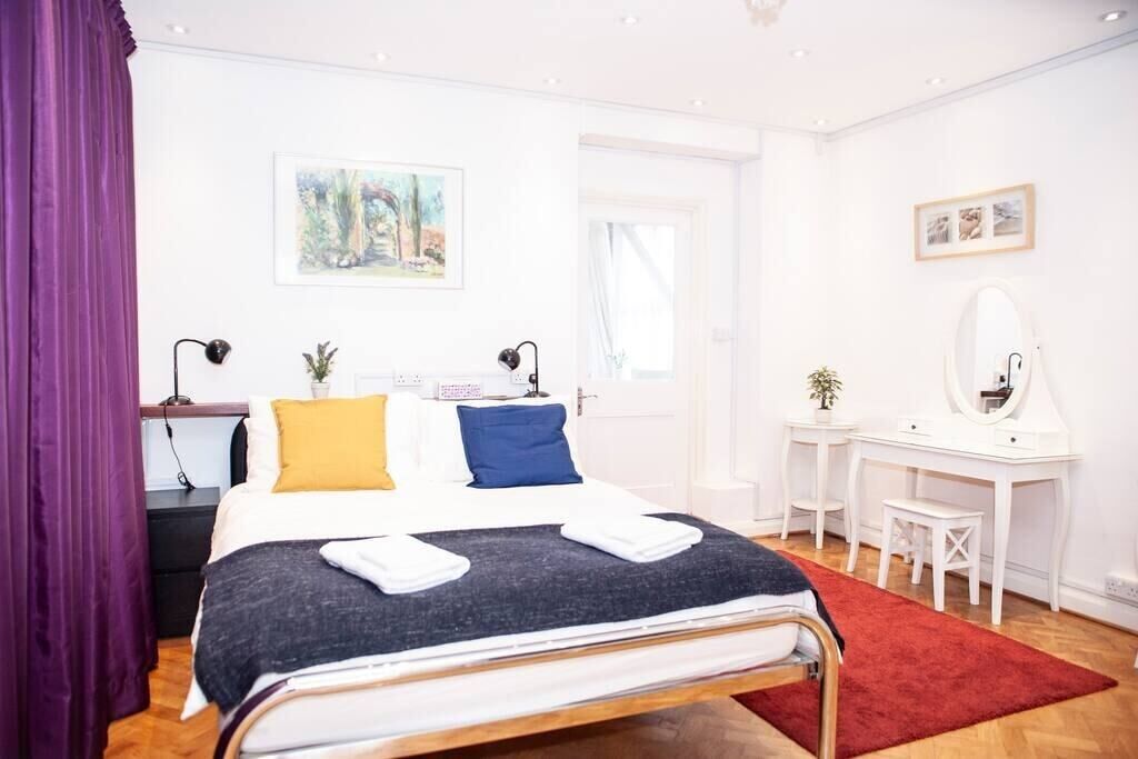 Une chambre à coucher avec un lit, des tables de chevet, un bureau, un miroir et un tapis rouge.