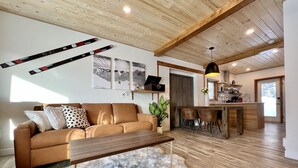 Un salón moderno con techo de madera, un sofá, una mesita de centro y una alfombra de piel.