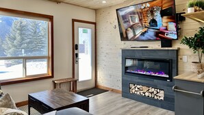 Una habitación acogedora con chimenea, televisión y vistas a un paisaje nevado.