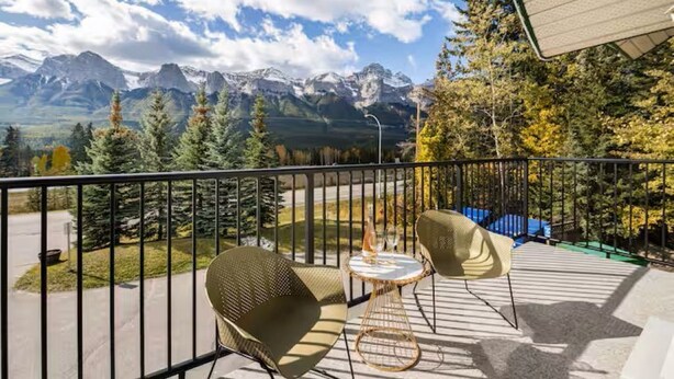 Un balcón con mobiliario exterior, una mesa y vistas a montañas.