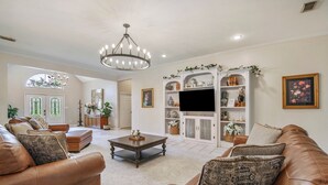 Un salón espacioso con un sofá de cuero marrón, una mesa de centro de madera y un mueble blanco con adornos.