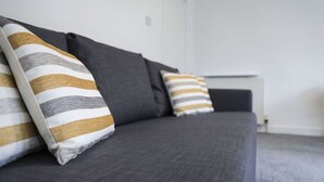A grey sofa with striped pillows in a neutral-toned room.