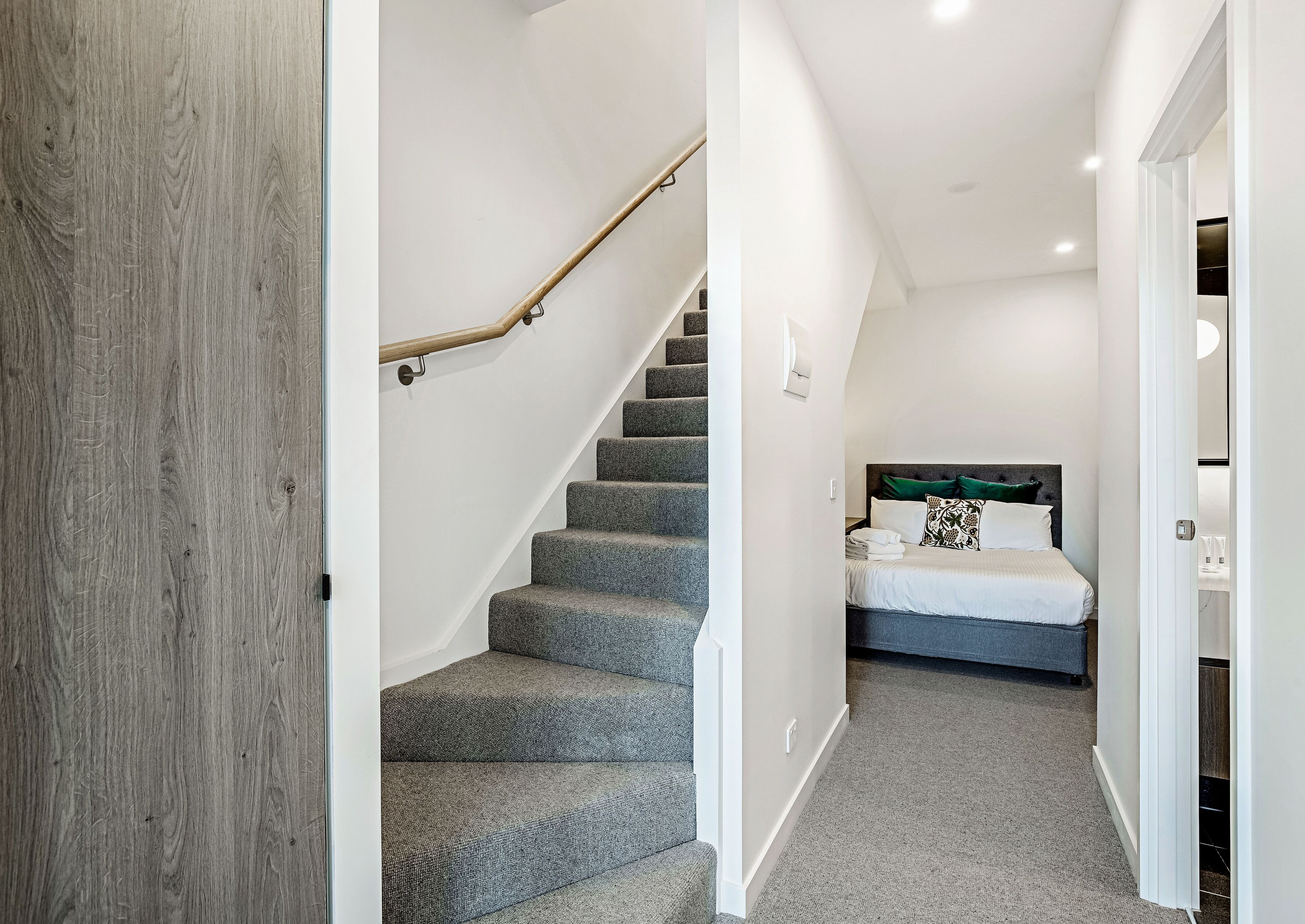 A staircase leading to a bedroom with a bed, a nightstand, and a headboard.