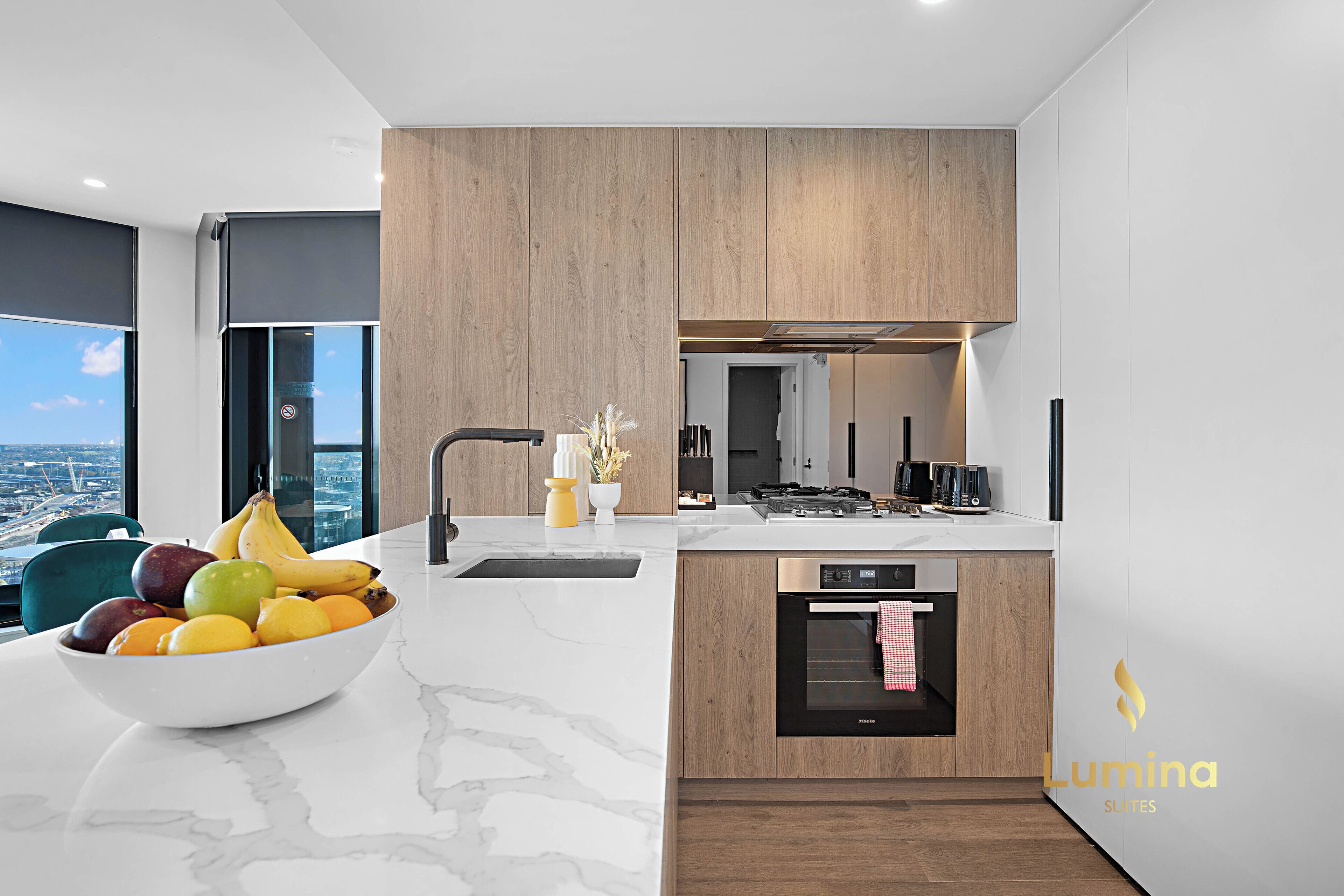 Uma cozinha moderna com bancada de mármore, armários de madeira e forno embutido.