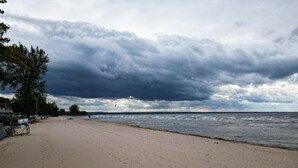 A beach with footprints, a lifeguard chair, and a cloudy sky. - Penthouse | Historic Oneida Lakefront Condo 5 (Blossvale)