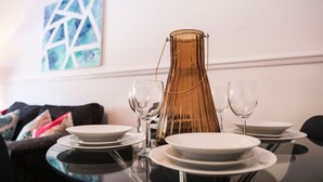 Een eettafel gedekt met borden, glazen en een lange, slanke, goudkleurige vaas.